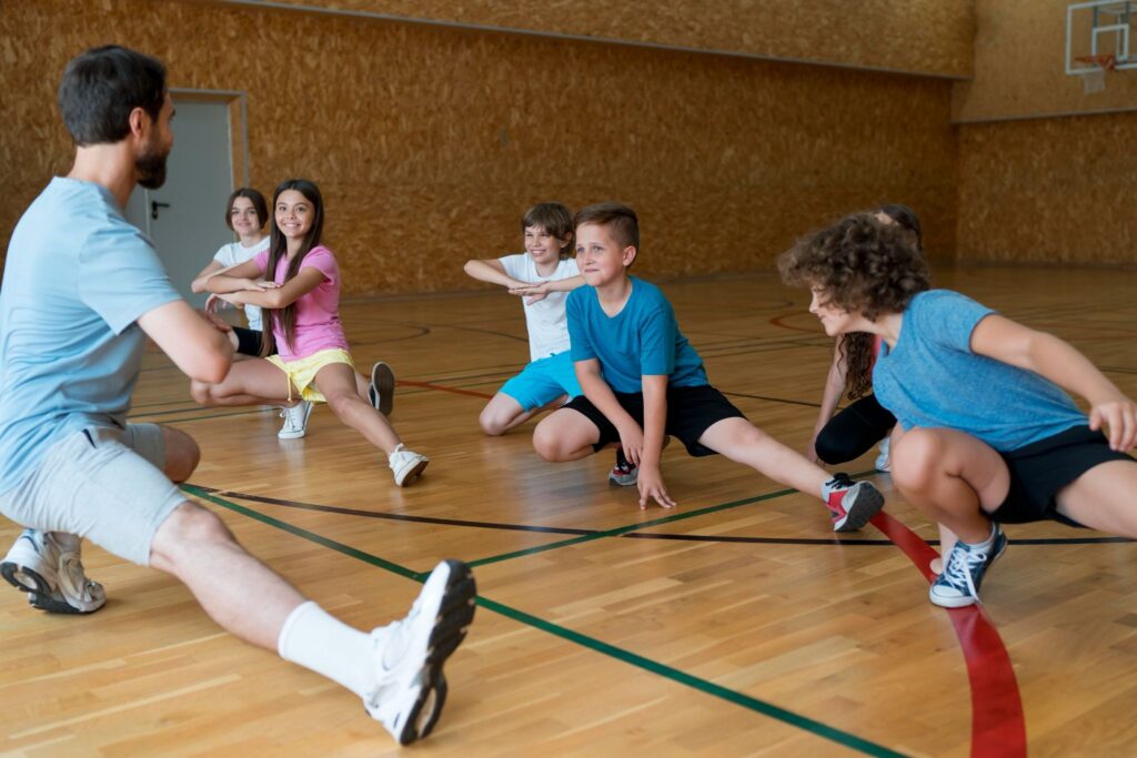 Crianças fazendo alongamento para aula experimental de esporte.