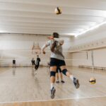 Uma partida de voleibol em um ginásio poliesportivo.