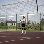 jovem com bola de vôlei nas mãos em uma quadra.