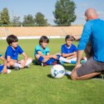 Professor orientando crianças em uma escolinha de futebol infantil.