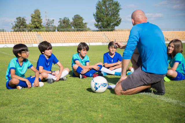 Professor orientando crianças em uma escolinha de futebol infantil.