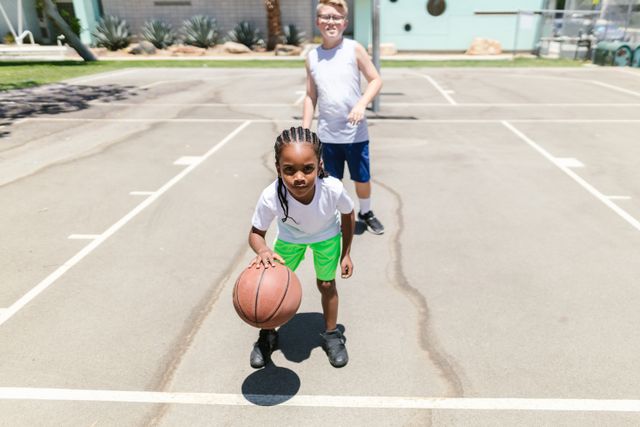 Crianças jogando basquete em uma quadra ao ar livre durante o dia.