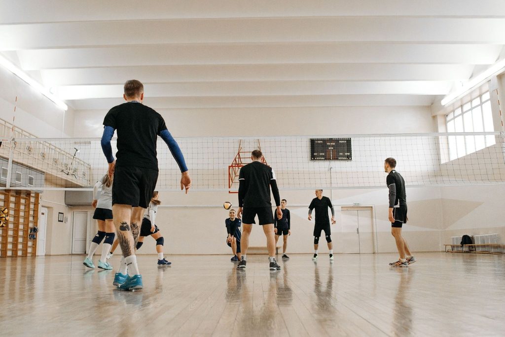 Equipe realizando treino de vôlei em quadra coberta.
