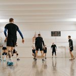 Equipe realizando treino de vôlei em quadra coberta.