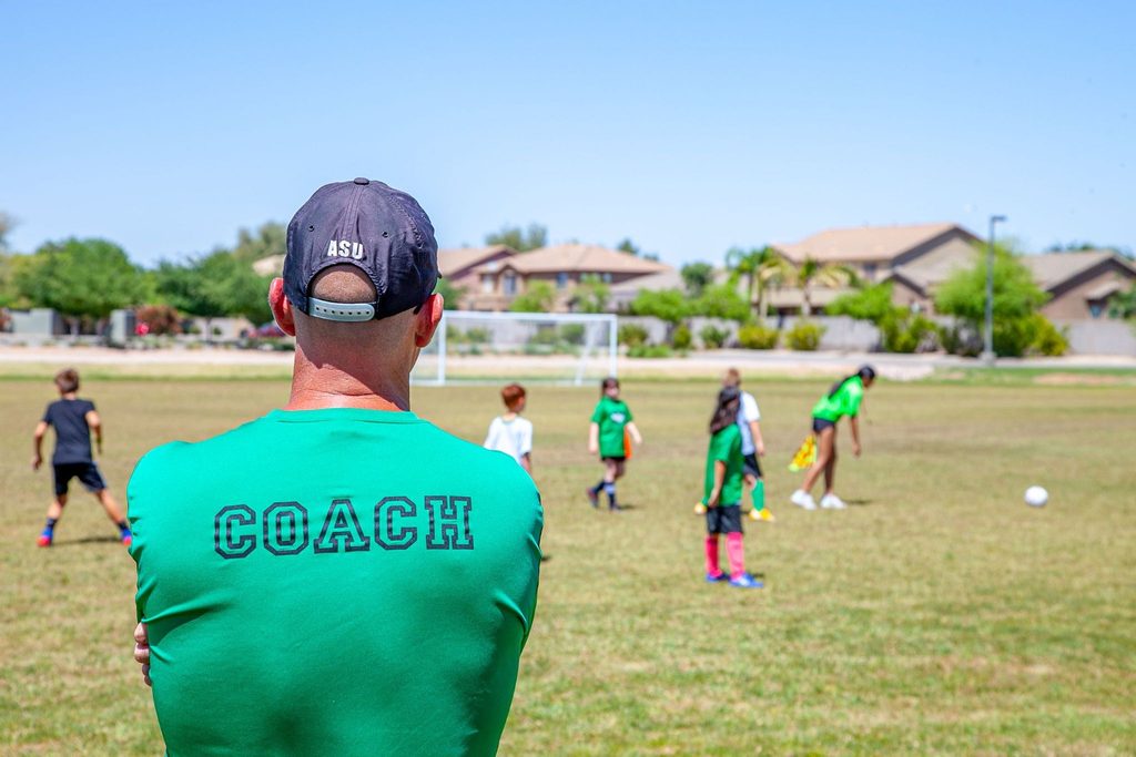 Professor acompanhando crianças durante uma atividade em campo.